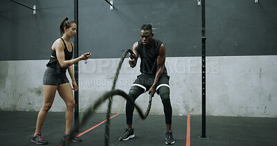 Buy stock photo Man, exercise and battle rope with personal trainer for strength training, endurance or cardio in gym. People, coach and stopwatch in health club with workout, challenge or support for fitness goals.