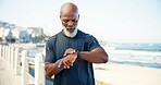 Black man, exercise and smart watch by beach with fitness app, heart rate tracker and step count. Mature person, workout break and timer by ocean with tech, monitor training or wellness on promenade.