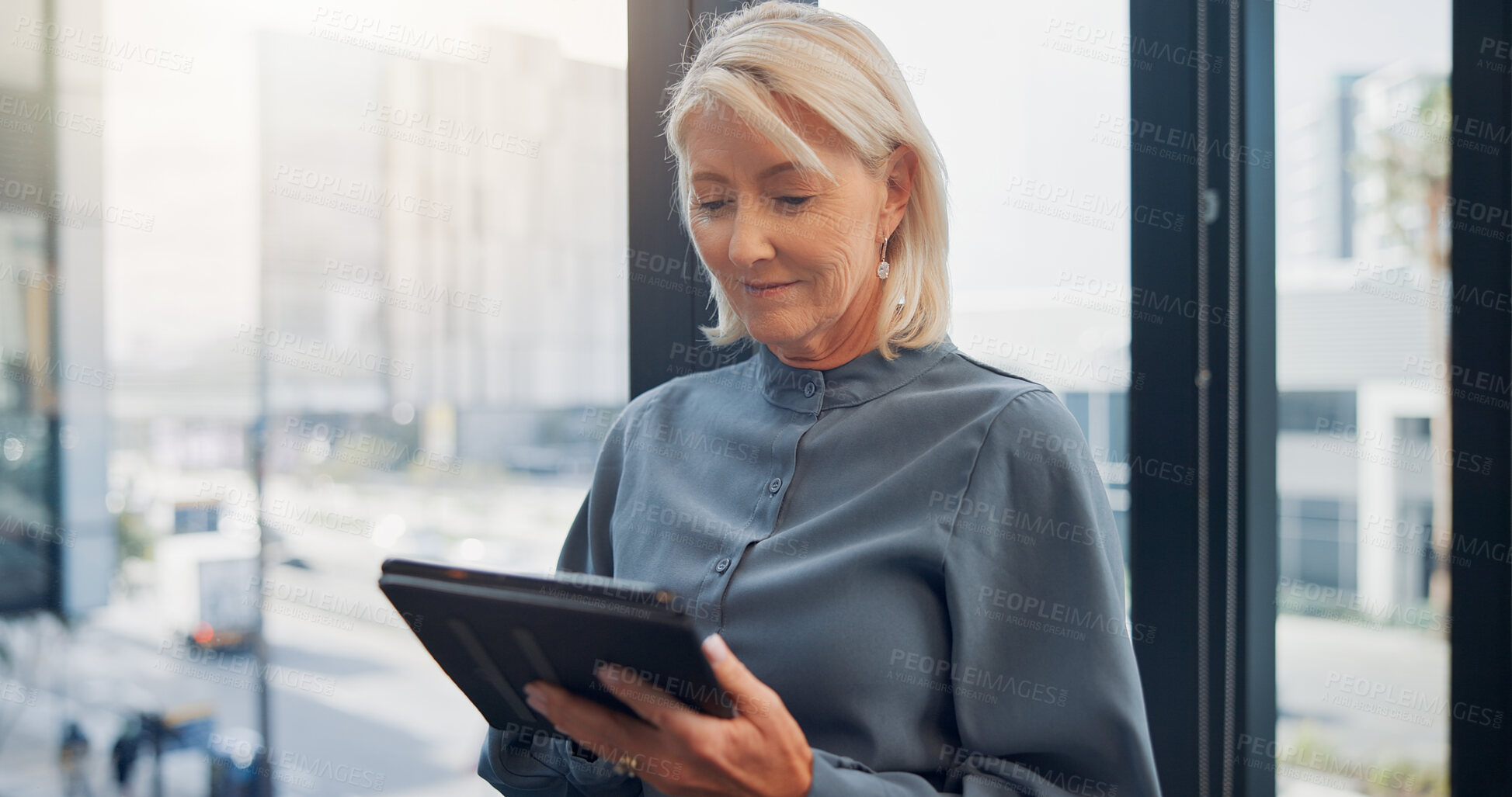 Buy stock photo Business, tablet and window with designer woman in city workplace for agenda, planning or research. App, design and schedule with mature employee in office for digital report or online review