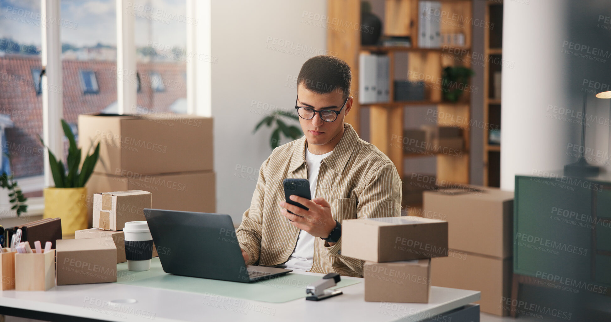 Buy stock photo Ecommerce, laptop and phone with man in logistics office together for delivery of online order. App, computer and distribution with supply chain employee in workplace for shipping or tracking