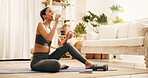Drinking water, exercise and yoga with woman in living room of home for holistic wellness or hydration. Beverage, bottle and break with yogi person on floor in apartment for health or recovery