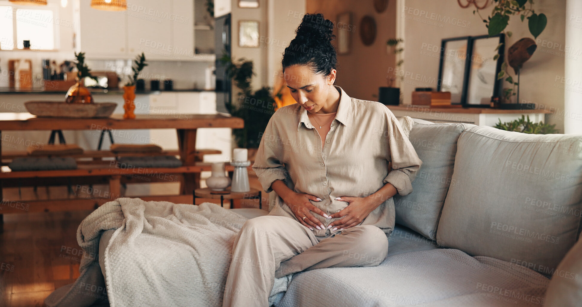 Buy stock photo Woman, stomach ache and sofa with pain for indigestion, period cramps or menstruation cycle in home. Female person, discomfort or sore tummy bug with gastrointestinal reflux for virus or diarrhea