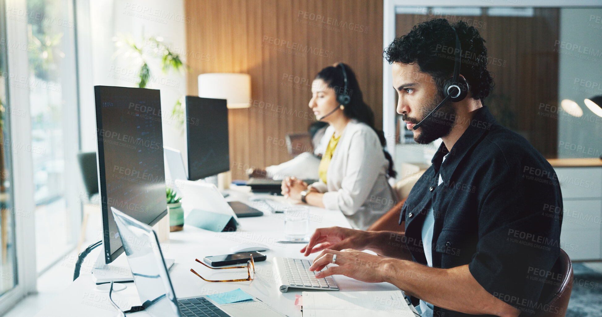 Buy stock photo Call center, computer and man in workplace, typing for customer service and headset for communication. Person, talking and employees in office, pc or discussion for online assistance and consultation