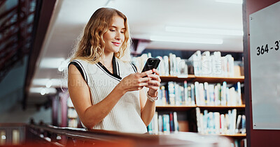 Buy stock photo Woman, student and texting with phone at library for education, smile and contact on web at college. Girl, smartphone and happy with chat, mobile app or social media on study break at university