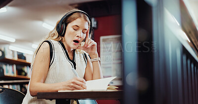 Buy stock photo Headphones, yawn or college student writing in library, course study notes or streaming music for fatigue. Tired, tech or woman with notebook for learning, educational podcast or exam preparation