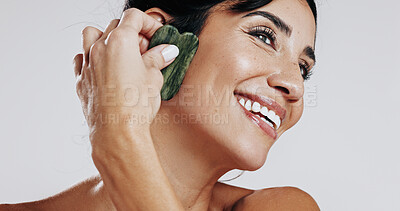 Buy stock photo Woman, gua sha and smile with skincare in studio for circulation, thinking and glow on white background. Mature person, stone tools and cosmetics with anti aging, lymphatic drainage and dermatology