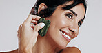 Woman, gua sha and smile with beauty in studio for circulation, thinking and skincare on white background. Mature person, stone tools and cosmetics with anti aging, lymphatic drainage and dermatology