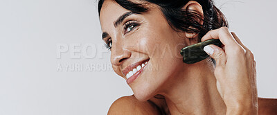 Buy stock photo Happy woman, facial and skincare with gua sha for anti aging massage on a white studio background. Female person, model or smile with jade or stone for beauty treatment, cosmetology or dermatology