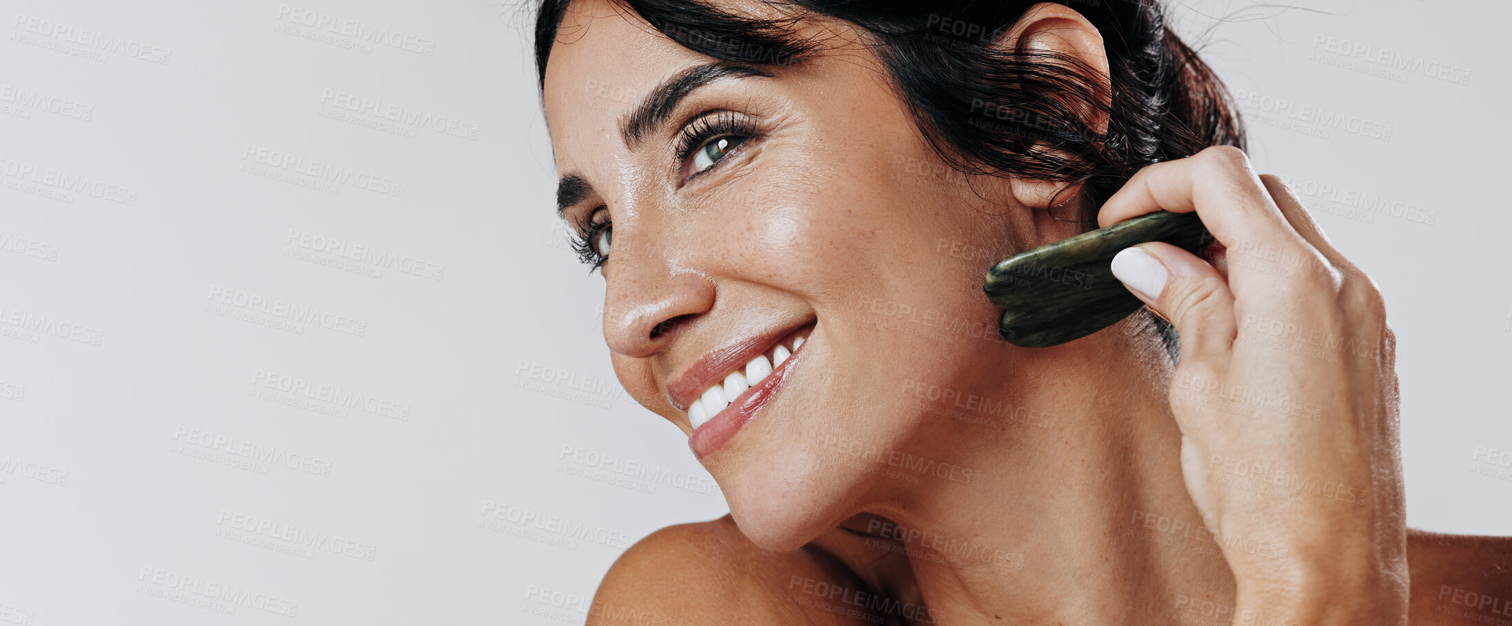 Buy stock photo Happy woman, facial and skincare with gua sha for anti aging massage on a white studio background. Female person, model or smile with jade or stone for beauty treatment, cosmetology or dermatology
