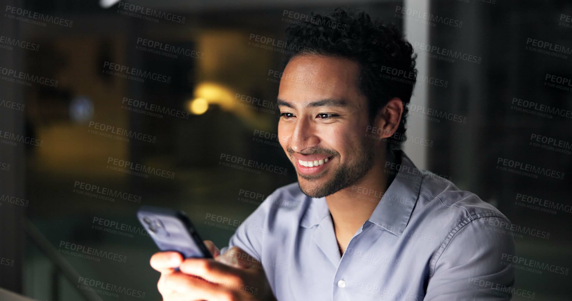Buy stock photo Night, man and smile in office with phone, journalist research and text message for story update. Late, person and typing in workplace with tech, check email and notification for feedback on article.