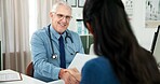 Shaking hands, consultation and doctor with woman in hospital with medical diagnosis in office. Paperwork, handshake and mature healthcare worker with female patient for planning treatment in clinic.