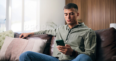 Buy stock photo Serious, reading and man with phone on couch, browsing social media and check notification on message app. Watch video, mobile and person with sad news post in home, internet and online communication