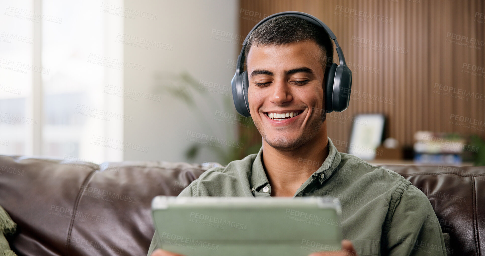 Buy stock photo Laugh, tablet and man on sofa with headphones for online videos, subscription and watching movies. Home, happy and person on digital tech for internet, website and streaming to relax on weekend