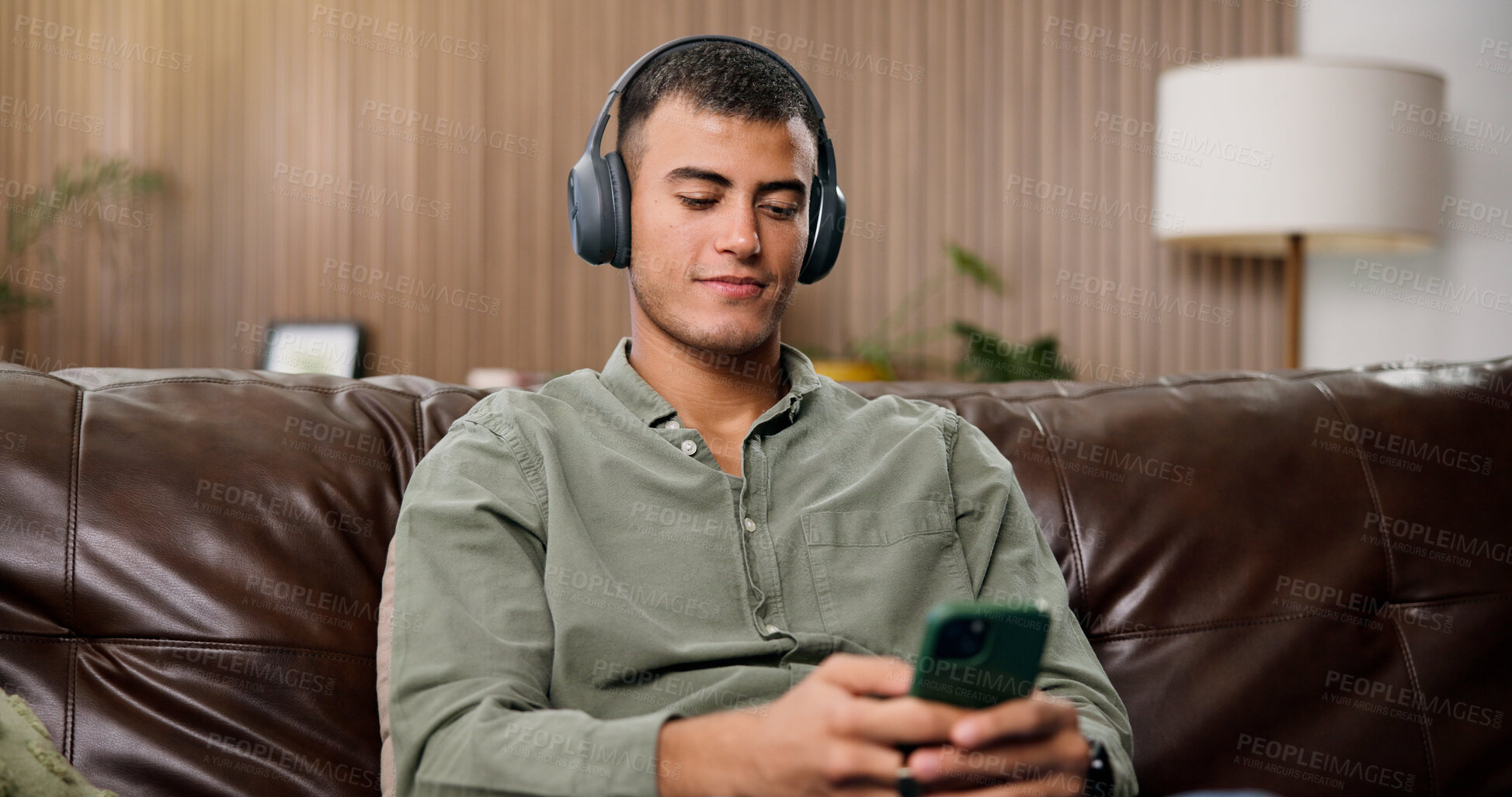 Buy stock photo Man, phone and relax with headphones on sofa for streaming, smile and sound in living room at house. Person, smartphone and listen to music with subscription, mobile app or audio on couch in home