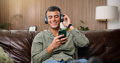 Buy stock photo Man, phone and happy with headphones on sofa for streaming, relax and sound in living room at house. Person, smartphone and listen to music with subscription, mobile app or texting on couch in home