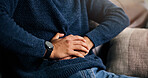 Man, hands or stomach ache with indigestion, constipation or diarrhea for pain on sofa in home. Closeup, male person or sore belly with gastrointestinal reflux for virus or bladder infection in house