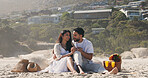Couple, holding hands and picnic with love at beach for romantic date, celebration and bonding together. Smile, people and embrace with flowers for romance, anniversary getaway and holiday at seaside