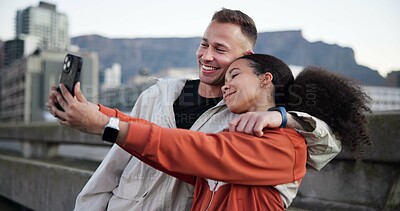 Buy stock photo Happy couple, fitness and phone with selfie in city with hug, love or bonding with break on bridge. People, runner and photography with mobile app, smile and rest for interracial relationship in town