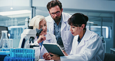 Buy stock photo Microscope, science and tablet with team in laboratory together for development or research. App, feedback and talking with scientist people at work on clinical trial, medical industry or study