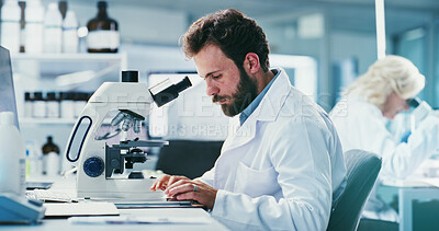 Buy stock photo Microscope, man and scientist in laboratory for pharmaceutical research, study or experiment. Biotechnology, professional and male biologist typing with clinical development, science or innovation.