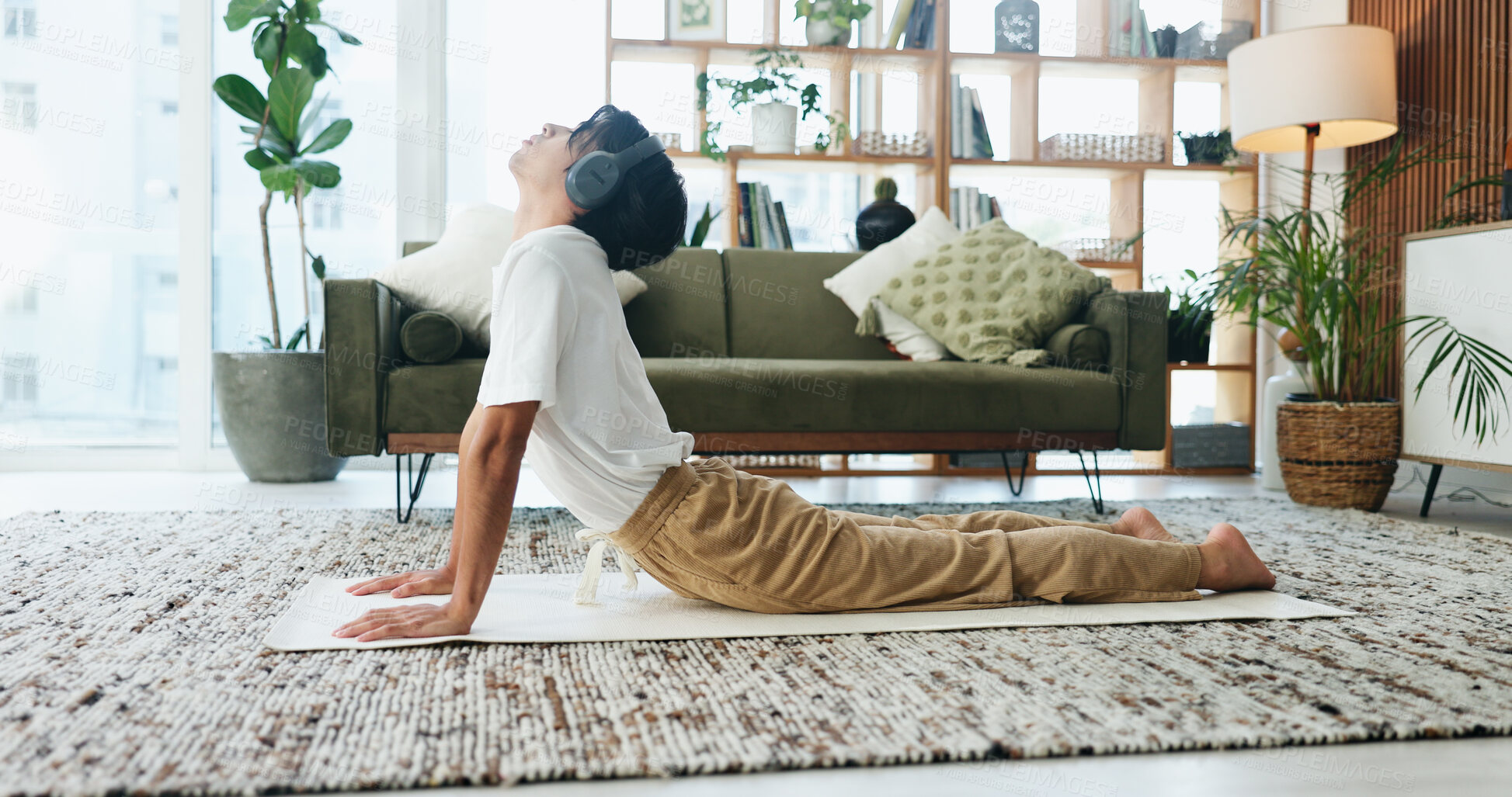 Buy stock photo Music, stretching and yoga with man on floor in home living room for exercise or wellness routine. Fitness, headphones and health with Asian person in cobra pose for balance or holistic activity