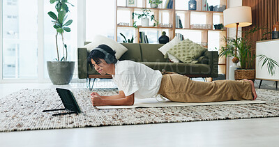 Buy stock photo Exercise, headphones and tablet with Asian man in home living room for health or training routine. Fitness, plank and video streaming with person on floor in apartment for online course or tutorial