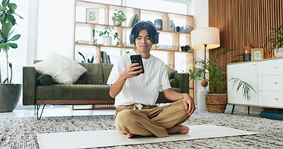 Buy stock photo Yoga mat, headphones and happy man with phone in home for meditation song, sound or pilates playlist. Mobile, music and Asian person on floor for fitness podcast, wellness audio or streaming service