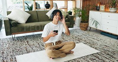Buy stock photo Yoga mat, headphones and happy man with mobile in home for subscription, sound or pilates playlist. Phone, music and Asian person on floor for fitness podcast, wellness audio or streaming service