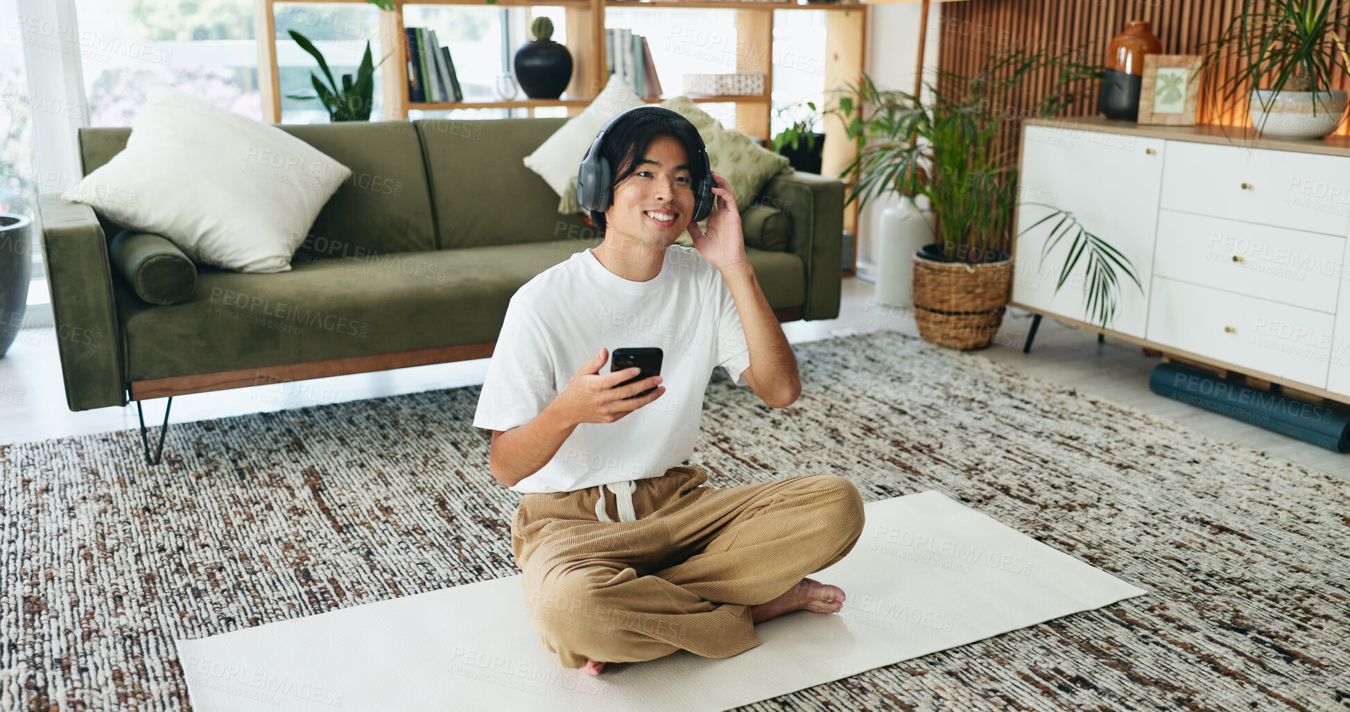 Buy stock photo Yoga mat, headphones and happy man with mobile in home for subscription, sound or pilates playlist. Phone, music and Asian person on floor for fitness podcast, wellness audio or streaming service