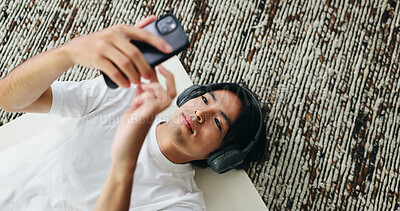 Buy stock photo Yoga mat, headphones and Asian man with phone in home for sound, pilates playlist and top view. Mobile, music and person on floor for fitness podcast, wellness audio or streaming service from above