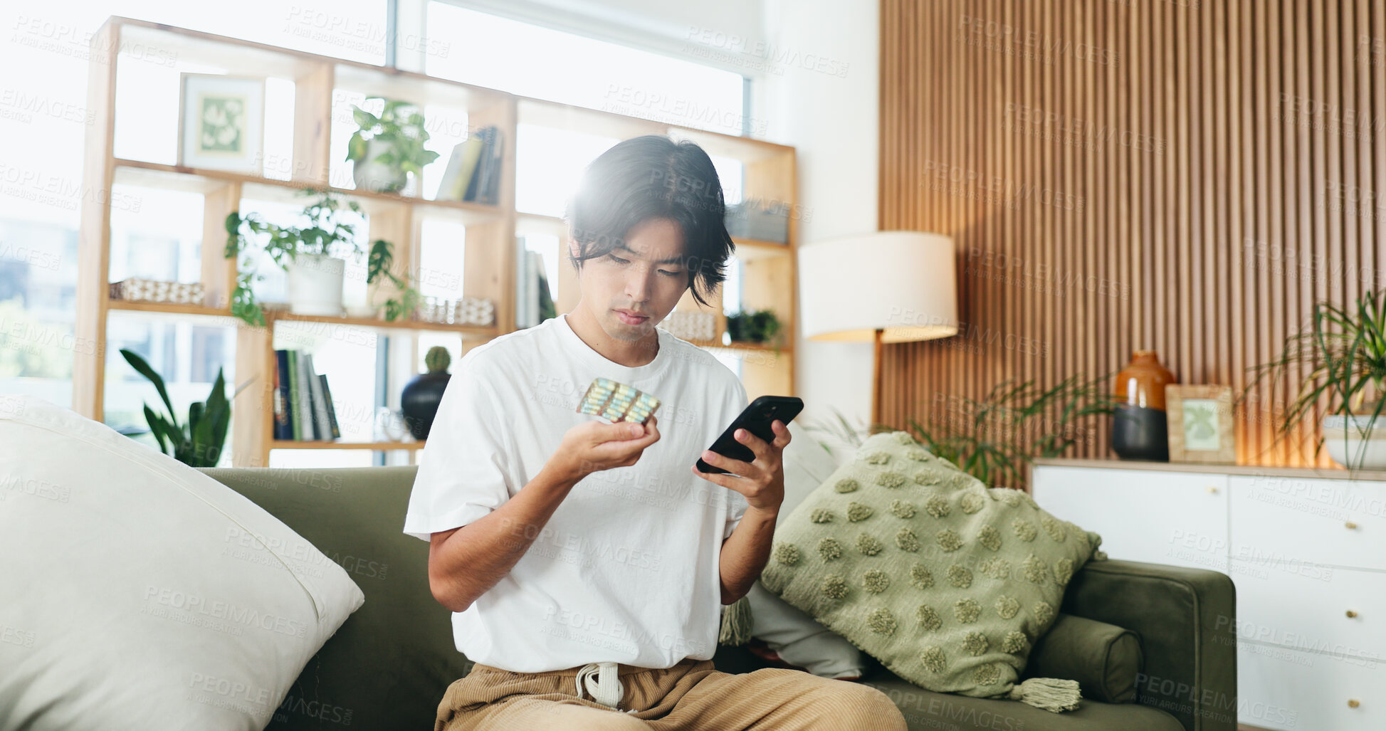 Buy stock photo Man, phone and pills on sofa with search for side effects, ingredients or allergies on web at home. Person, smartphone and check medicine on mobile app, supplements and drugs for wellness in house