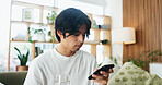 Break, phone and water with Asian man on sofa in home living room for hydration or social media. Drink, glass and relax with person scrolling mobile app for browsing, connection or online search