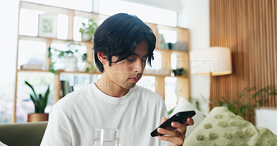 Buy stock photo Break, phone and water with Asian man on sofa in home living room for hydration or social media. Drink, glass and relax with person scrolling mobile app for browsing, connection or online search