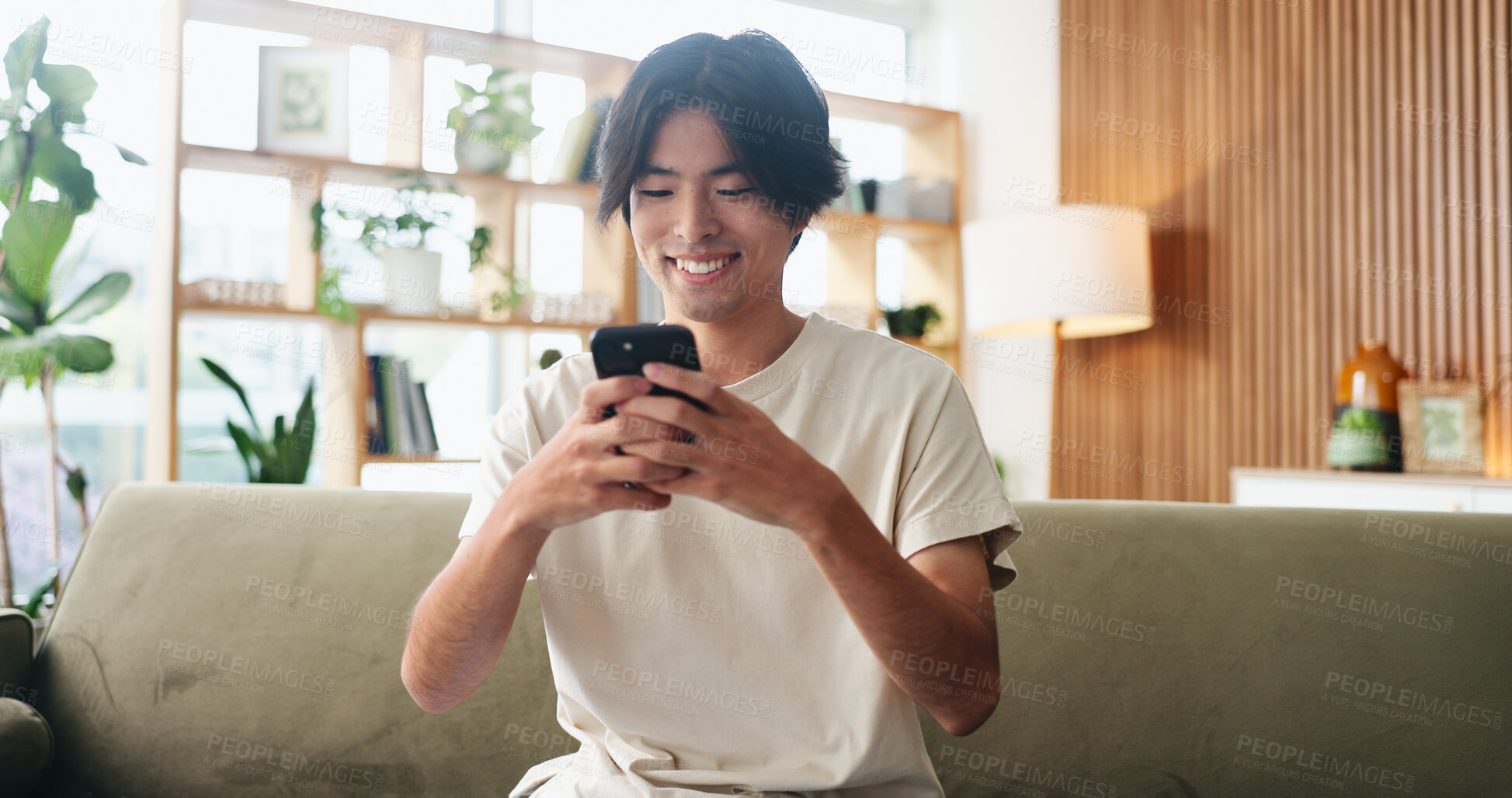 Buy stock photo Texting, smile or Asian man in house with phone, online chat or communication on dating site. Happy, conversation or person in home with tech, digital app or connection on matchmaking platform.
