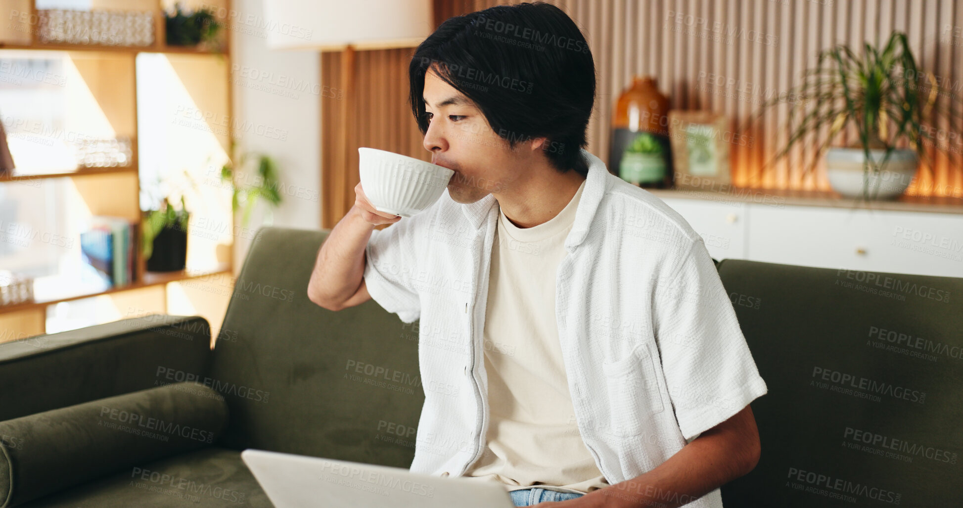 Buy stock photo Coffee, laptop and man on sofa in home with online application for university scholarship. Education, relax and Asian male student drinking warm beverage with computer for studying in living room.