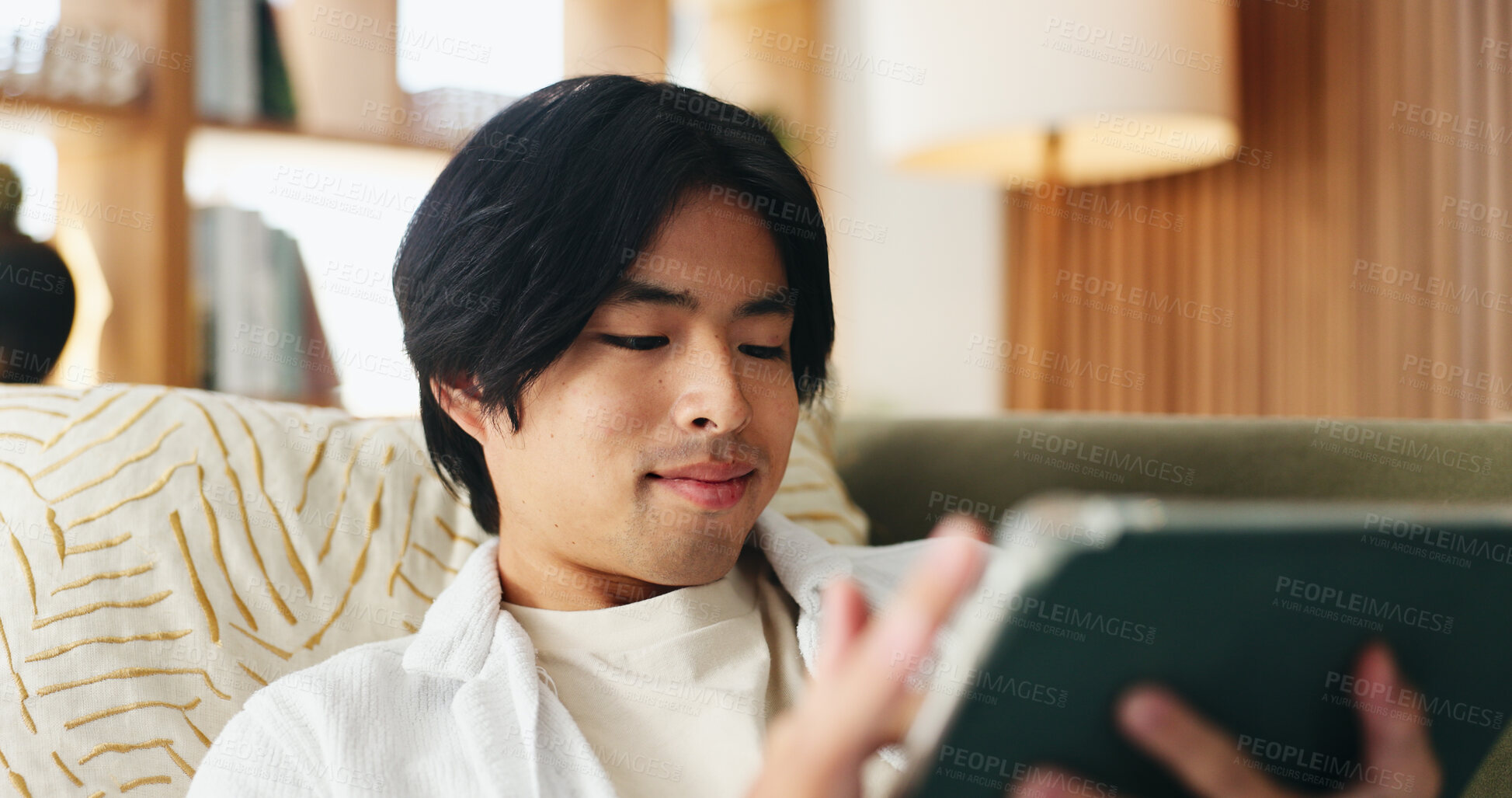 Buy stock photo Education, reading and tablet with Asian man on sofa in home living room for distance learning. App, online study and scrolling with university student in apartment for development or growth