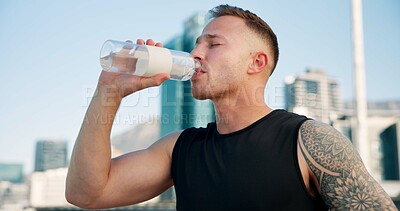 Buy stock photo Man, fitness and drinking with water in city for hydration, sustainability or thirst. Active, male person or runner with mineral liquid, beverage or refreshment for rest or recovery in an urban town