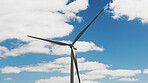Clouds, blue sky and wind turbine on farm for power, renewable energy and carbon footprint. Background, landscape and windmill for sustainability, electricity and conservation for environment