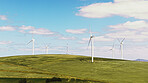 Blue sky, nature and windmills outdoor by grass for renewable energy, sustainable or eco friendly. Field, clouds and wind turbines for natural resource with economic development in countryside.