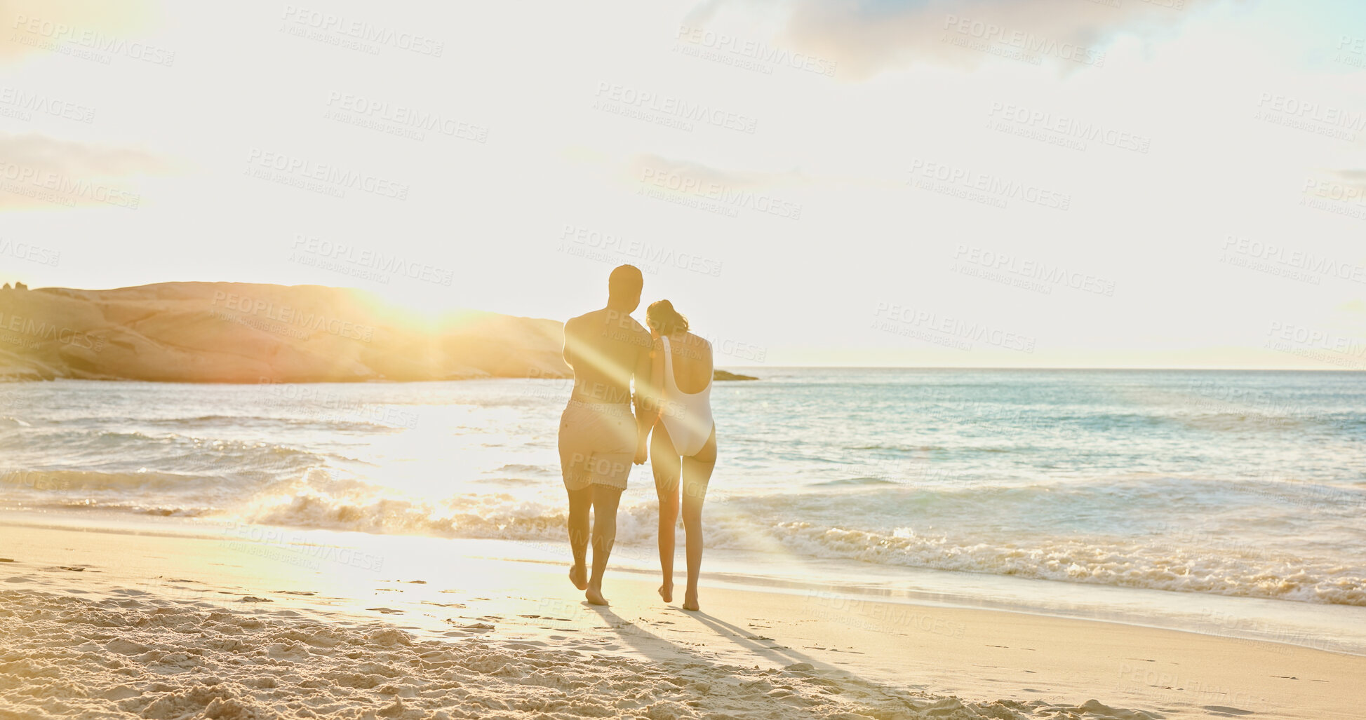 Buy stock photo Couple, walk and sunset at beach on holiday with back, bonding or holding hands for love in summer. Man, woman and partnership with swimwear, sunshine or space in sky with waves on seaside vacation