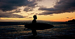 Silhouette, surfboard and walking with person on beach for holiday, sports hobby or weekend getaway. Activity, sunset and vacation with surfer outdoor at coast for fitness or training in summer