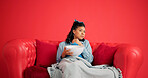 Woman, watching tv and popcorn with sofa on studio with portrait, scared and space on red background. Girl, relax and eating snack with anxiety, fear or blanket for horror movie on couch in Mexico