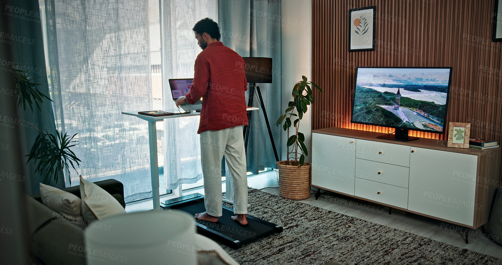 Buy stock photo Walking pad, home and back of man for remote work, productivity and healthy habit for career. Creative, freelance and person on treadmill with laptop for research, online project and website review