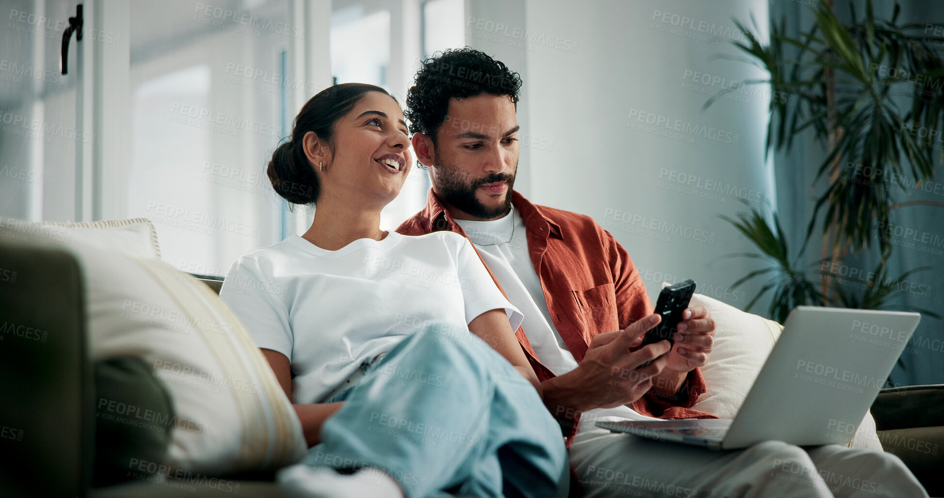 Buy stock photo Happy, talking and couple on sofa with tech for social media, networking and bonding on weekend. Marriage, relax and man with woman on phone and laptop for internet, website and connection in home