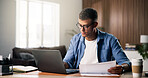 Documents, laptop and remote work with man in home study for planning, research or review. Computer, paperwork and report with freelance employee at desk in apartment for small business startup