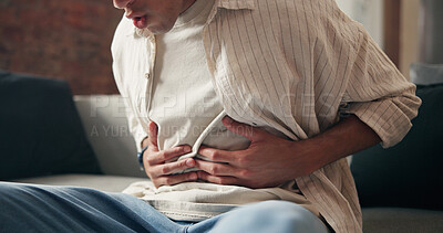Buy stock photo Man, hands and sick in house with stomach ache, indigestion and inflammation from diarrhea problem. Person, abdomen pain and medical issue on couch with constipation, bowel discomfort and bloating.