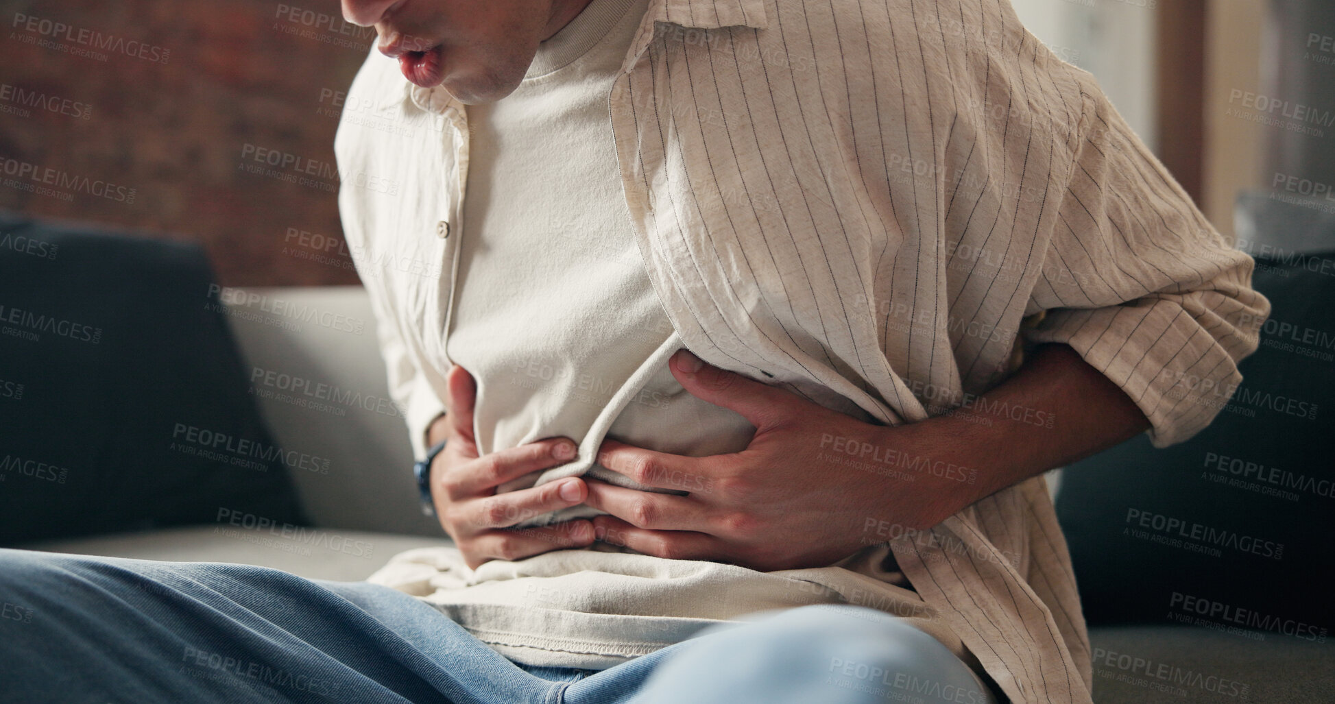 Buy stock photo Man, hands and sick in house with stomach ache, indigestion and inflammation from diarrhea problem. Person, abdomen pain and medical issue on couch with constipation, bowel discomfort and bloating.