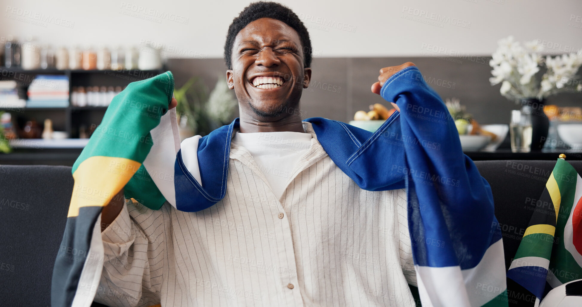 Buy stock photo Black man, South African flag and celebration in lounge, soccer and cheering for victory. Fan, shouting or person in home, football or excited for score lead, tournament or supporter with happiness