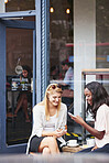 Phone, friends and women at cafe outdoor, relax and check social media post on hangout together. Coffee shop, happy people and mobile app, text notification and customers reading blog on internet