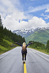 Travel adventure woman celebrates arms raised  at view of majestic road landscape on exploration discover beautiful earth